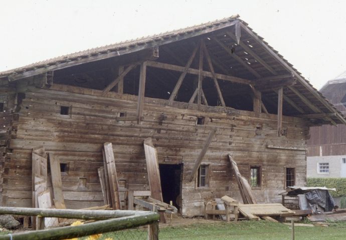 Bei der Abtragung in Helming, 1980. An das Haus gelehnt stehen bereits abgebaute Bretter vom Dachstuhl, von dem jetzt das Gerüst sichtbar ist.