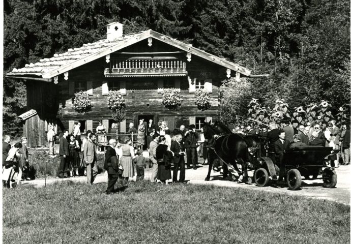 Bei der Eröffnung im Freilichtmuseum, 1984. Blick auf das blumengeschmückte Zischkhäusl. Die Ehrengäste werden in einer Pferdekutsche zum Haus gefahren. Um das Haus stehen die Gäste.