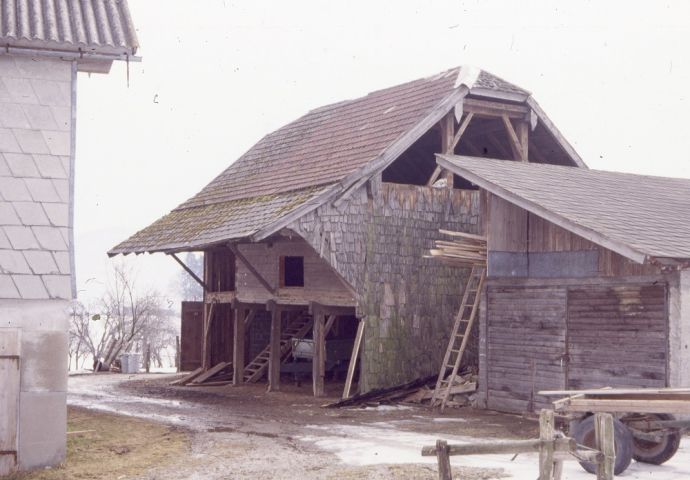 Die Meindlhütte an ihrem ursprünglichen Standhort in Anthering. Man sieht die Unterstände  mit geöffneten Toren, neben der Meindlhütte steht ein Holzschopf.