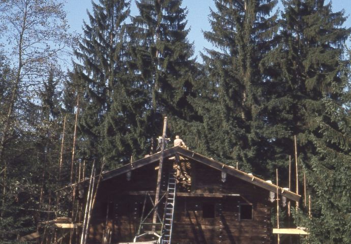 Beim Aufbau im Freilichtmuseum, 1979. Frontaler Blick auf das Zischkhäusl, das bereits fertig aufgestellt ist. Seitlich stehen noch die Gerüste. Das Dack wird gedeckt.